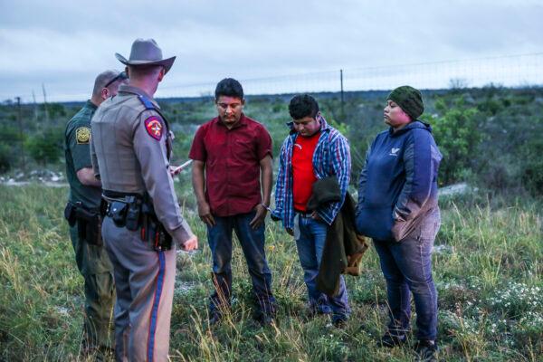  A Border Patrol agent picks up three illegal aliens after Texas state troopers arrested two U.S. citizen smugglers who were transporting them to San Antonio, in Kinney County, Texas, on Oct. 20, 2021. (Charlotte Cuthbertson/The Epoch Times)