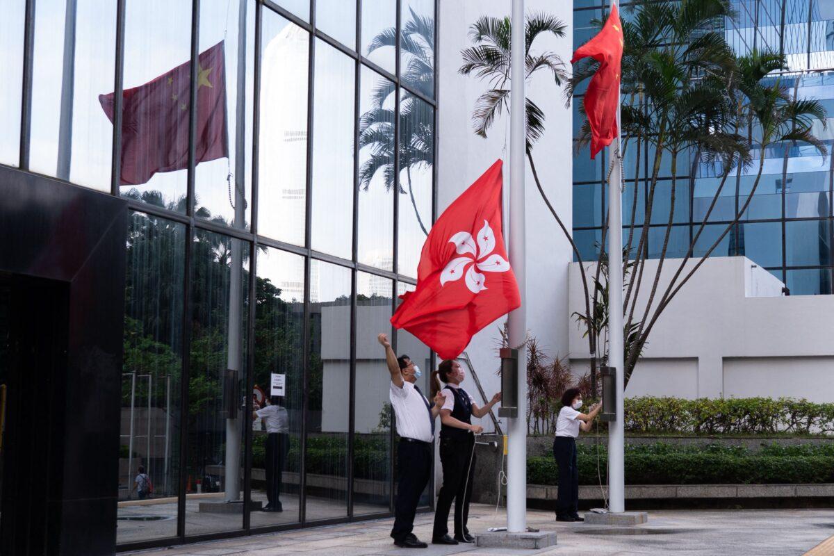 Workers raise the Chinese (top-R) and Hong Kong flags outside of a building in Hong Kong on Oct. 16, 2021. (Bertha Wang/AFP via Getty Images)