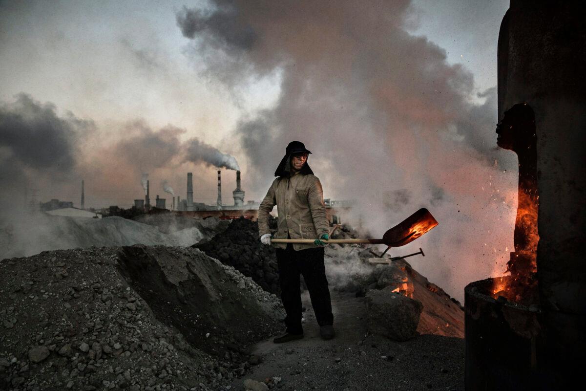 A Chinese laborer loads coal into a furnace as smoke and steam rise from an unauthorized steel factory in Inner Mongolia, China, on Nov. 3, 2016. (Kevin Frayer/Getty Images)