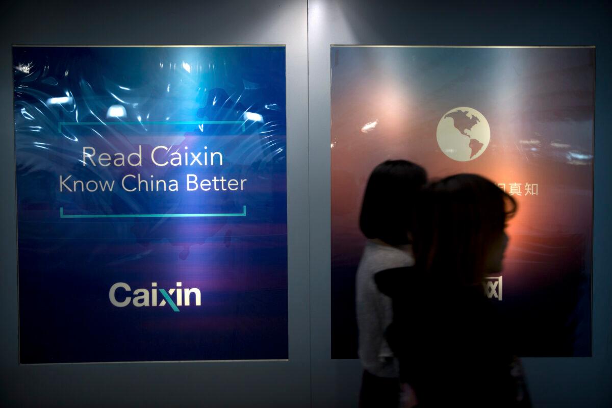 Staffers walk past a billboard at the Caixin Media offices in Beijing on Jan. 18, 2018. (Mark Schiefelbein/AP Photo)