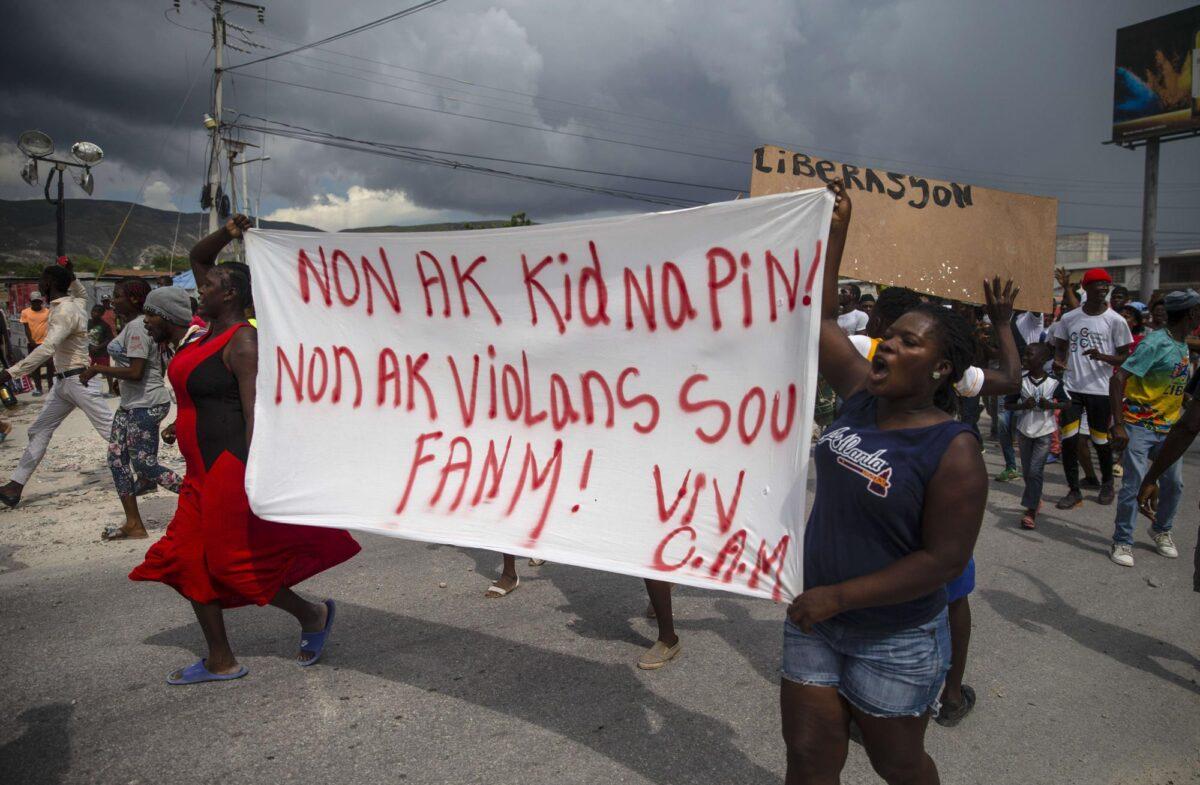 People protest carrying a banner with a message that reads in Creole: "No to kidnappings, no to violence against women ! Long live Christian Aid Ministries," demanding the release of kidnapped missionaries, in Titanyen, north of Port-au-Prince, Haiti, on Oct. 19, 2021. (Joseph Odelyn/AP Photo)