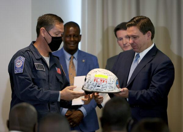 Florida Gov. Ron DeSantis receives a signed helmet from Brandon Webb, Battalion Chief, Special Operations Division Miami-Dade County Fire Rescue during an event to give out bonuses to first responders held at the Grand Beach Hotel Surfside on August 10, 2021 in Surfside, Florida. DeSantis gave out some of the $1,000 checks that the Florida state budget passed for both first responders and teachers across the state. (Joe Raedle/Getty Images)