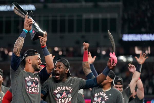 Atlanta Braves' Eddie Rosario holds the MVP trophy as he celebrates with Guillermo Heredia after winning Game 6 of baseball’s National League Championship Series against the Los Angeles Dodgers in Atlanta, on Oct. 24, 2021. (Ashley Landis/AP Photo)