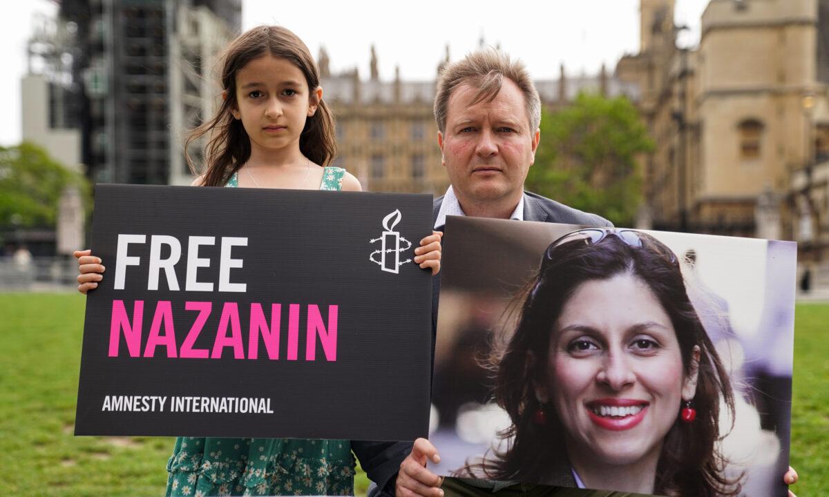 Richard Ratcliffe and his daughter Gabriella hold signs to mark the 2,000th day Nazanin Zaghari-Ratcliffe has been detained in Iran, in Parliament Square, London, on Sept. 23, 2021. (Kirsty O'Connor/PA)