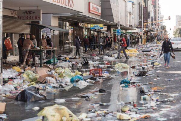 A few people walk in Dr. Pixley Ka Seme street filled with dirt and filth caused after five days of looting in Durban, South Africa, on July 14, 2021. (Rajesh Jantilal/AFP via Getty Images)