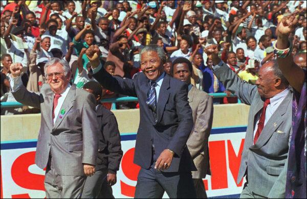 South African Communist Party (SACP) leader Joe Slovo (L) and anti-apartheid leader and African National Congress (ANC) member Nelson Mandela (C) salute supporters in Soweto, South Africa, on May 6 1990. (Walter Dhladhla/AFP via Getty Images)