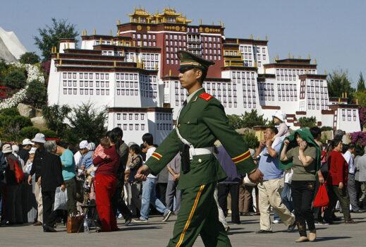 A paramilitary soldier on patrol marches past a crowd gathered in front of a replica of Tibet's most revered landmark Potala Palace on Sept. 26, 2006. (Frederic J. Brown/AFP via Getty Images)