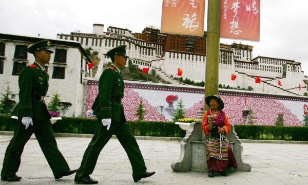 A Tibetan worshiper looks at Chinese police officers patrolling in front of Potala Palace, in Lhasa, Tibet, China, on June 20, 2008. (Guang Niu/Getty Images)