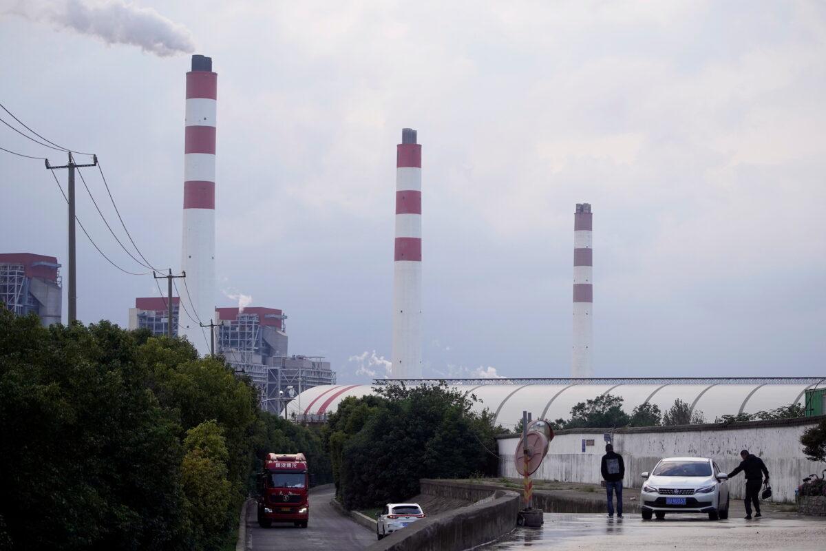 Men stand by a car near a coal-fired power plant in Shanghai, on Oct. 21, 2021. (Aly Song/Reuters)