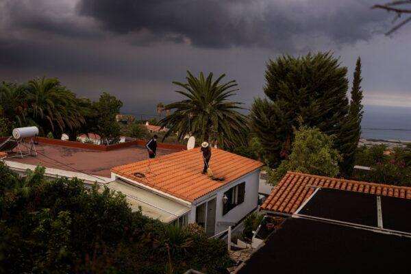 Residents clean the ash from the roof of their house as lava flows from a volcano on the Canary island of La Palma, Spain, on Oct. 27, 2021. (Emilio Morenatti/AP Photo)