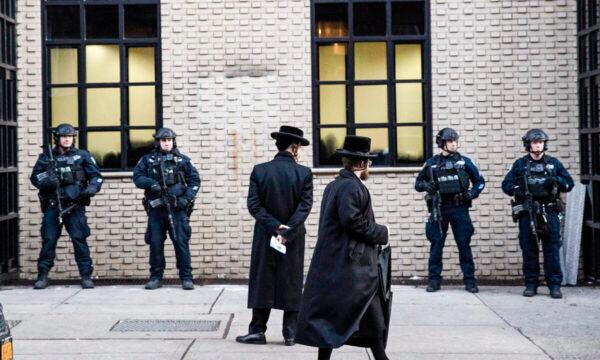Orthodox Jewish men pass New York City police guarding a Brooklyn synagogue prior to a funeral for Mosche Deutsch in New York on Dec. 11, 2019. (Mark Lennihan/AP Photo)