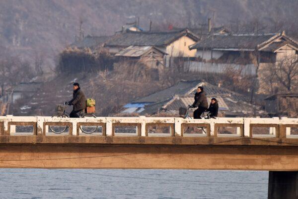North Korean villagers ride bicycles on a bridge, as seen from a boat on the Yalu River, opposite Hekou, in China's northeast Liaoning Province on Feb. 24, 2019. (Greg Baker/AFP via Getty Images)