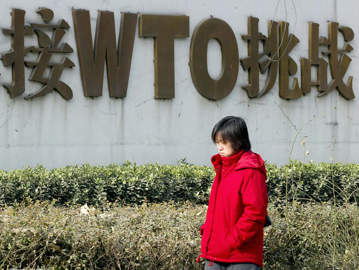 A Chinese woman walks pass a billboard boasting of China's World Trade Organization (WTO) membership along street in Beijing on Dec. 19, 2003. (Goh Chai Hin/AFP/Getty Images)