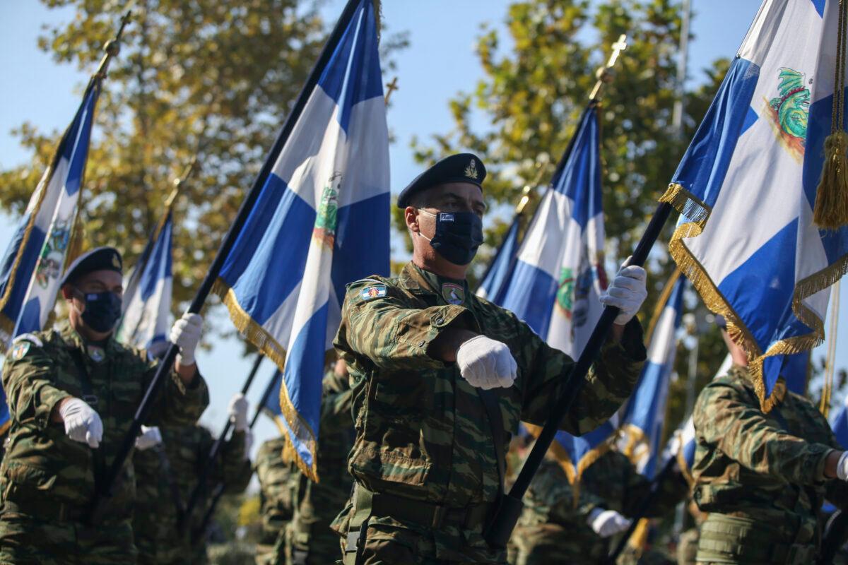 Greek military officers hold Greek flags during a military parade at the northern port city of Thessaloniki, Greece, on Oct. 28, 2021. (Giannis Papanikos/AP Photo)