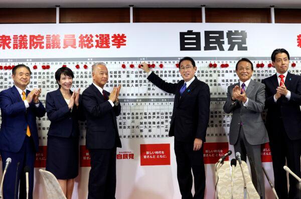 Japan's Prime Minister and ruling Liberal Democratic Party leader Fumio Kishida (3rd-R) poses with key party members as he puts rosettes by successful general election candidates' names on a board at the party headquarters in Tokyo on Oct. 31, 2021. (Behrouz Mehri/Pool via AP)