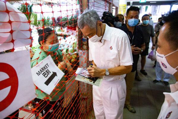 Singapore's Prime Minister Lee Hsien Loong, autographs a photo for a resident during a walkabout, ahead of the general election in Singapore, on July 3, 2020. (Ore Huiying/Getty Images)