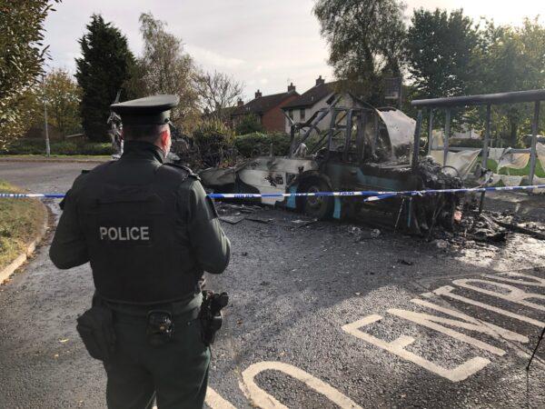 A police officer watches the remains of a bus that was hijacked and set alight in Newtownards, Northern Ireland on Nov. 1, 2021.(David Young/PA)