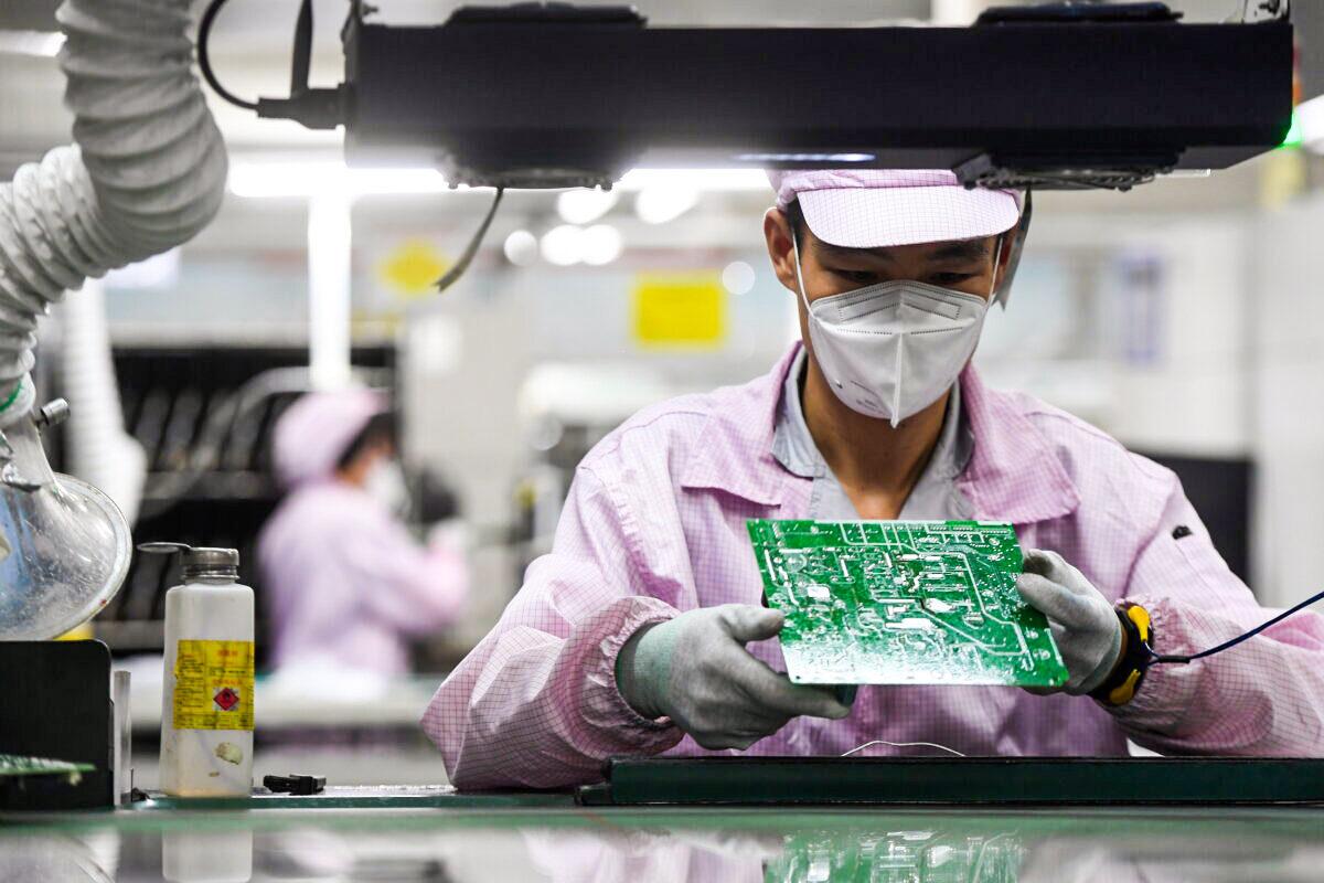 An employee inspects a circuit board on the controller production line at a Gree factory, following the COVID-19 outbreak in Wuhan, Hubei Province, China, on Aug. 16, 2021. (CD via Reuters)