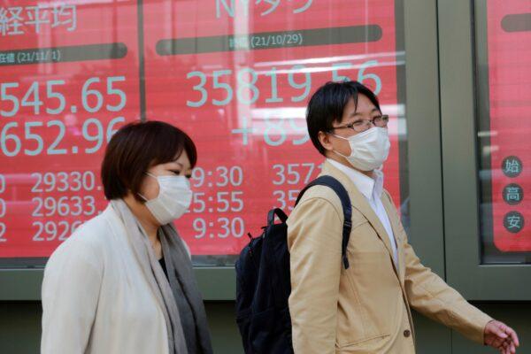 People walk by an electronic stock board of a securities firm in Tokyo, Japan on Nov. 1, 2021. (Koji Sasahara/AP Photo)