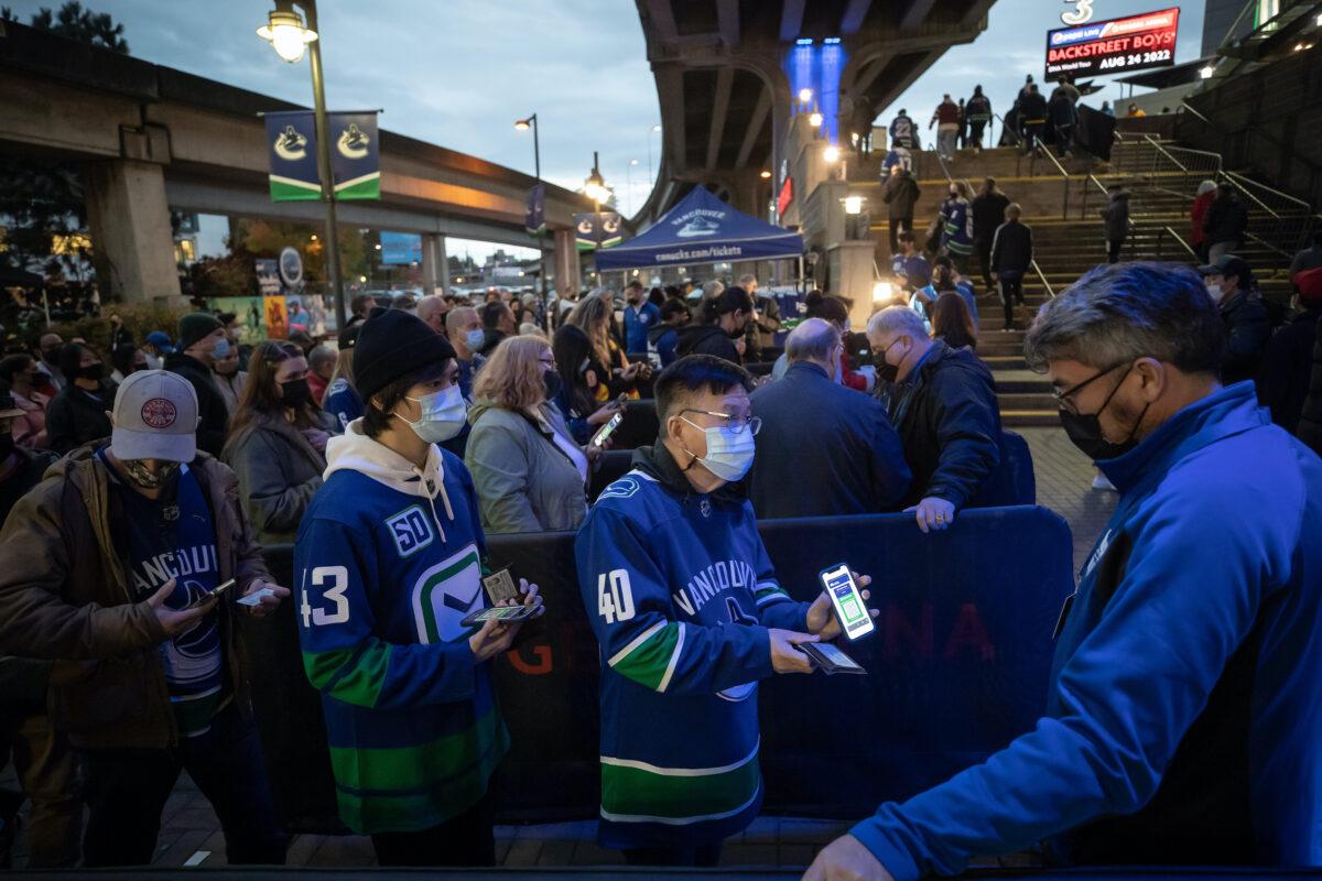 A fan shows his vaccine passport before entering Rogers Arena for the Vancouver Canucks NHL hockey game against the Minnesota Wild in Vancouver on Oct. 26, 2021. (The Canadian Press/Darryl Dyck)
