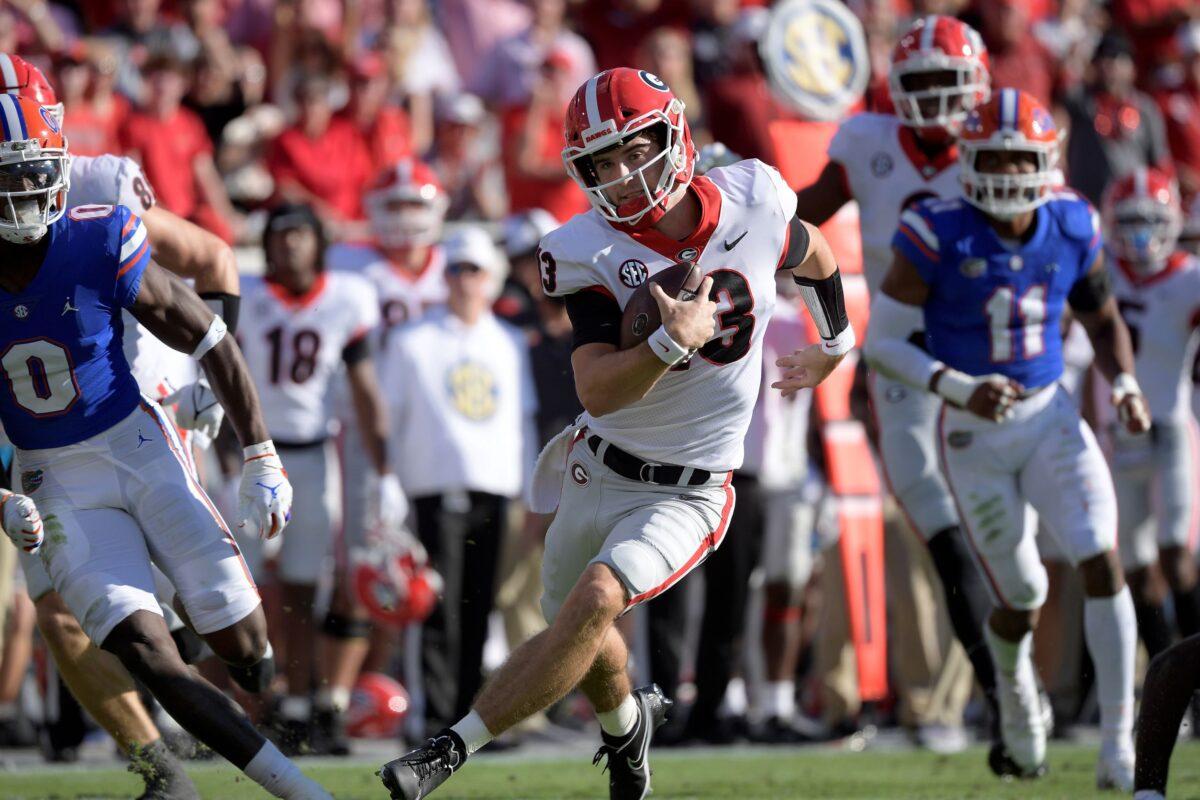 Georgia quarterback Stetson Bennett (13) scrambles for yardage in front of Florida safety Trey Dean III (0) and linebacker Mohamoud Diabate (11) during the first half of an NCAA college football game in Jacksonville, Fla., on Oct. 30, 2021, (Phelan M. Ebenhack/AP Photo)