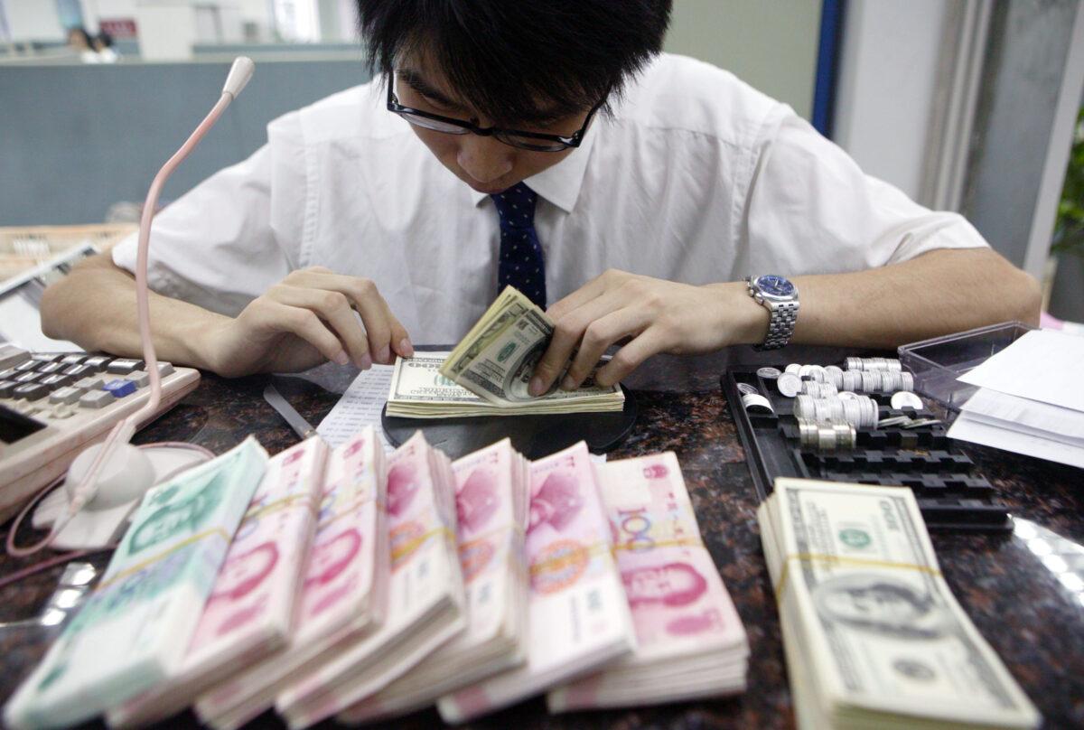 A clerk counts stacks of Chinese yuan and U.S. dollars at a bank in Shanghai on July 22, 2005. (China Photos/Getty Images)