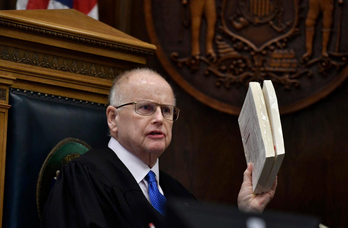 Judge Bruce Schroeder uses large stacks of paper to tell the jury how large the book on technical evidence he read during Kyle Rittenhouse's trial at the Kenosha County Courthouse in Kenosha, Wis., on Nov. 3, 2021. (Sean Krajacic/The Kenosha News via AP)