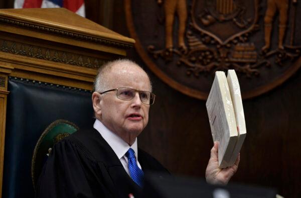 Judge Bruce Schroeder uses large stacks of paper to tell the jury how large the book on technical evidence he read during Kyle Rittenhouse's trial at the Kenosha County Courthouse in Kenosha, Wis., on Nov. 3 2021. (Sean Krajacic/The Kenosha News via AP)