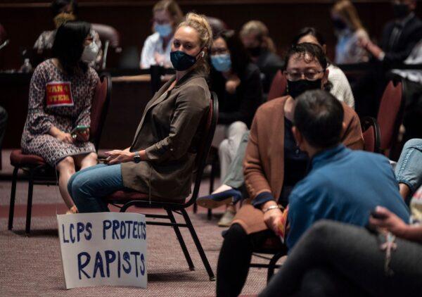 A woman sits with her sign during a Loudoun County Public Schools (LCPS) board meeting in Ashburn, Virginia, on Oct. 12, 2021. (Andrew Caballero-Reynolds/AFP via Getty Images)