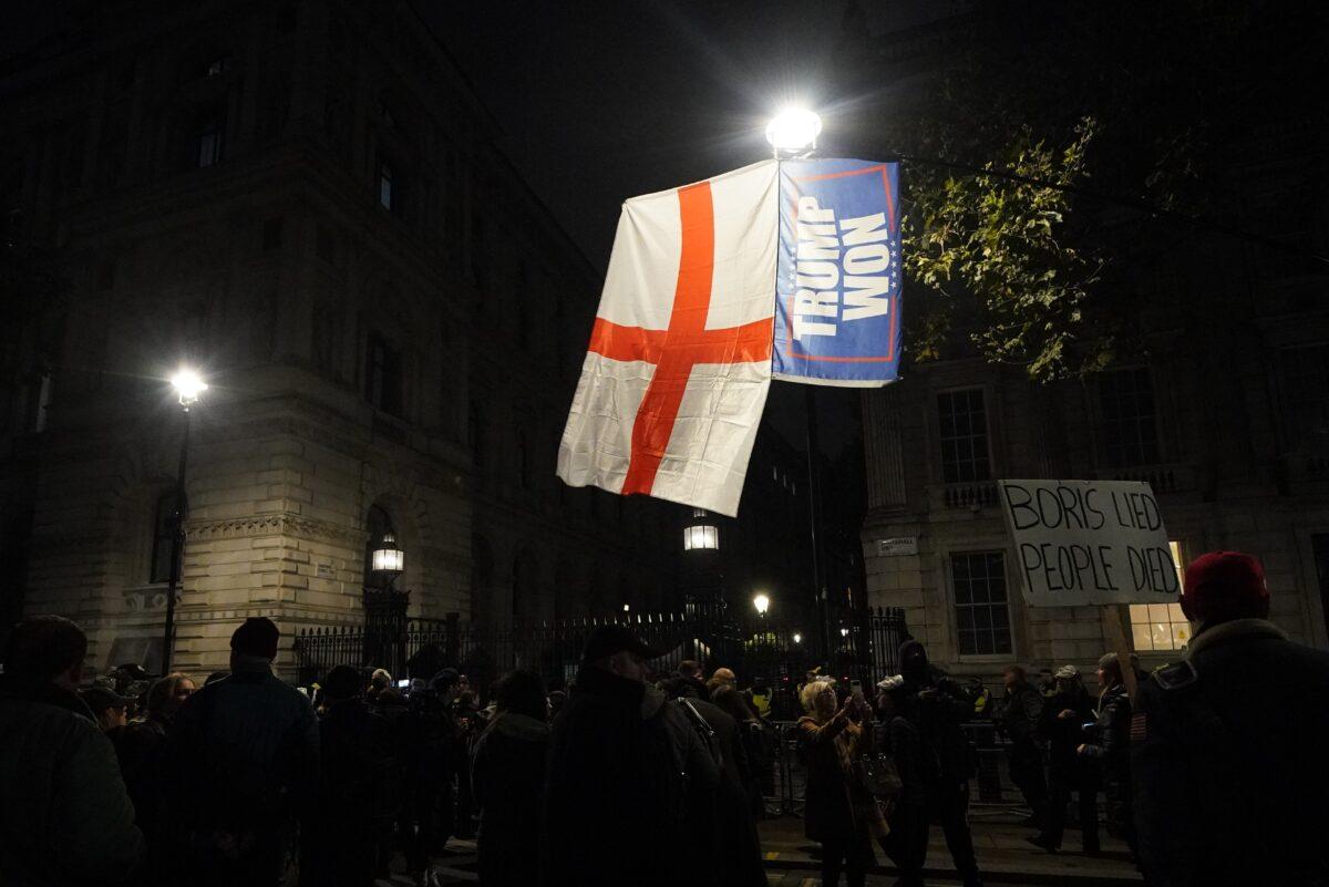 A St. George's Flag and “Trump won” flag, fly over people taking part in the Million Mask March outside Downing Street, London, on Nov. 5, 2021. (PA)