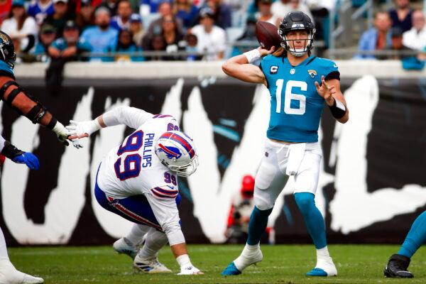 Jacksonville Jaguars quarterback Trevor Lawrence (16) throws a pass as he is pressured by Buffalo Bills defensive tackle Harrison Phillips (99) during the first half of an NFL football game in Jacksonville, Fla., on Nov. 7, 2021. (Stephen B. Morton/AP Photo)