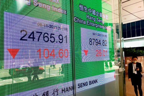 A woman walks past a bank's electronic board showing the Hong Kong share index at Hong Kong Stock Exchange on Nov. 8, 2021. (Vincent Yu/AP Photo)
