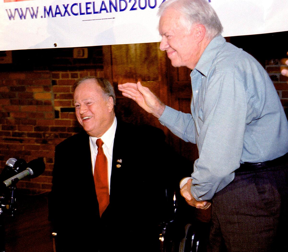 Former President Jimmy Carter (R) gives U.S. Sen. Max Cleland (D-Ga.) a standing ovation during Cleland's campaign rally in Carter's rural hometown of Plains, Ga., on Oct. 25, 2002. (Walter Petruska/AP Photo)
