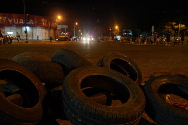 Improvised roadblock made of tires, with police lights in the background on Nov. 9, 2021 (Cesar Calani Cosso/The Epoch Times)