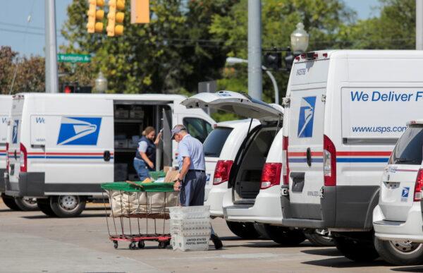 United States Postal Service (USPS) workers load mail into delivery trucks outside a post office in Royal Oak, Mich., on Aug. 22, 2020. (Rebecca Cook/Reuters)
