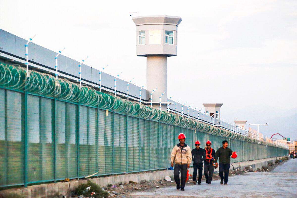 Workers walk by the perimeter fence of what is officially known as a vocational skills education center in Dabancheng, Xinjiang, China, on Sept. 4, 2018. (Thomas Peter/Reuters)