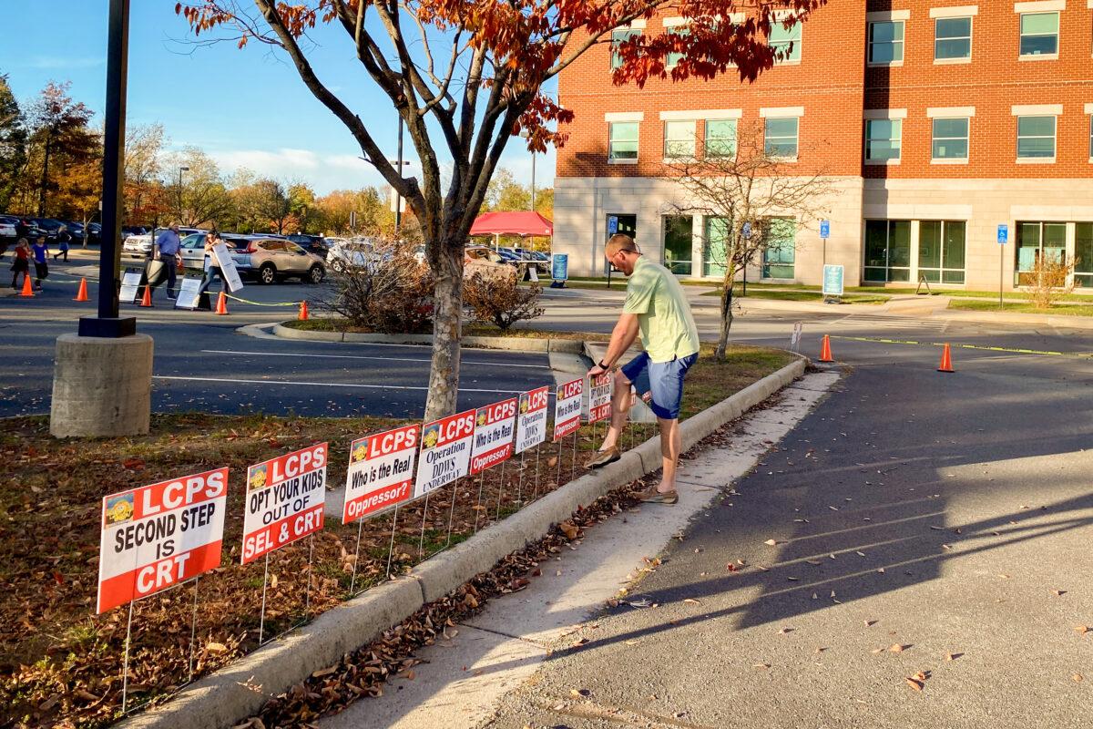 A Loudoun County resident sets up anti-CRT signs in front of the county school administration building in Ashburn, Va., on Nov. 9, 2021. (Terri Wu/The Epoch Times)