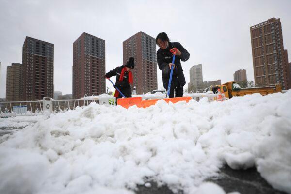 In this photo released by Xinhua News Agency, workers shovel snow at an expressway toll station in Shenyang, northeast China's Liaoning Province, Nov. 9, 2021. (Yang Qing/Xinhua via AP)