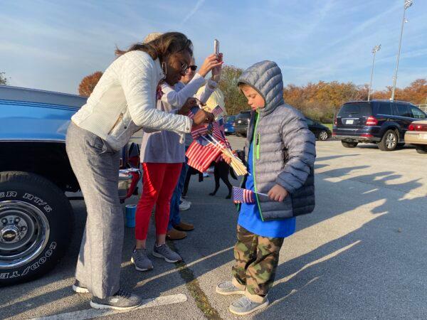 Austin Riddell, a fourth-grader at Redbud Run Elementary School, gives an American flag to Virginia Lt. Governor-Elect Winsome Sears at a Veterans Day event in Winchester, Va., on Nov. 11, 2021. (Terri Wu/The Epoch Times)