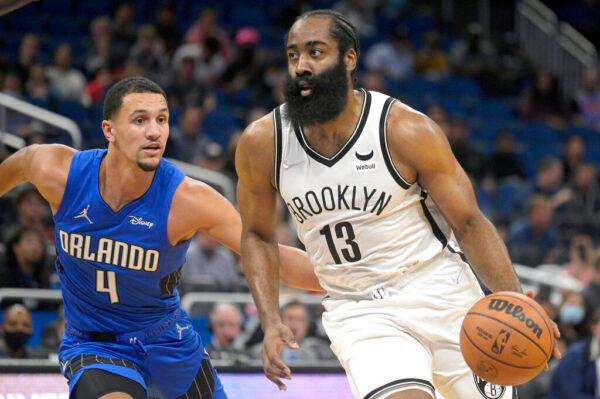 Brooklyn Nets guard James Harden (13) drives to the basket in front of Orlando Magic guard Jalen Suggs (4) during the first half of an NBA basketball game in Orlando, Fla., on Nov. 10, 2021. (Phelan M. Ebenhack/AP Photo)