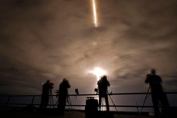 Photographers are silhouetted as a SpaceX Falcon 9 rocket with the Crew Dragon attached lifts off, on Nov. 10, 2021. (Chris O'Meara/AP Photo)