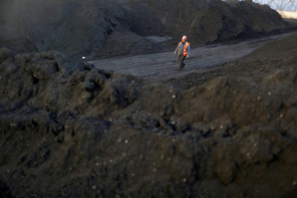 A worker walks past coal piles at a coal coking plant in Yuncheng, Shanxi Province, China, on Jan. 31, 2018. (William Hong/Reuters)