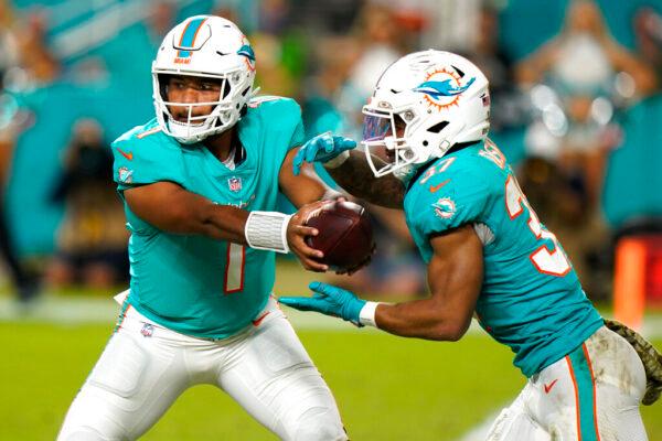 Miami Dolphins quarterback Tua Tagovailoa (1) hands the ball to running back Myles Gaskin (37) during the second half of an NFL football game against the Baltimore Ravens, in Miami Gardens, Fla., on Nov. 11, 2021. (Wilfredo Lee/AP Photo)