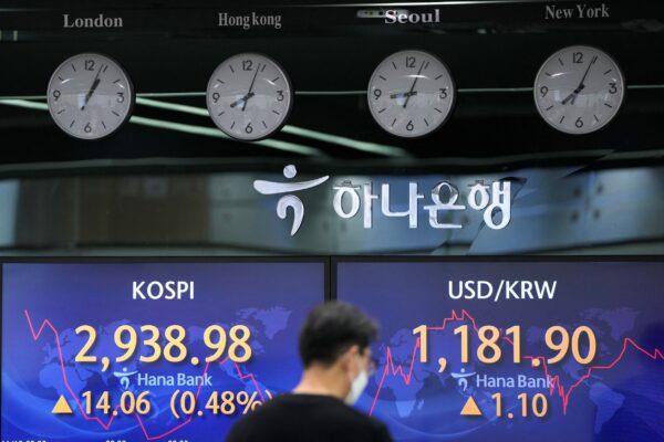 A currency trader walks by the screens showing the Korea Composite Stock Price Index (KOSPI), (L), and the foreign exchange rate between U.S. dollar and South Korean won at a foreign exchange dealing room in Seoul, South Korea on Nov. 12, 2021. (Lee Jin-man/AP Photo)