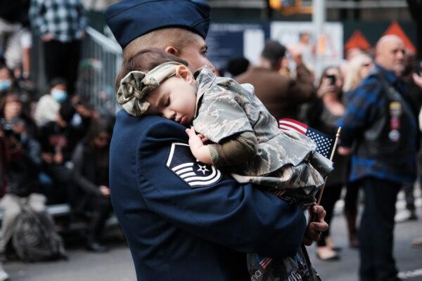 George Garcia, Master Sgt. USAF, holds his daughter while marching in the Veterans Day Parade in New York City, on Nov. 11, 2021. (Spencer Platt/Getty Images)