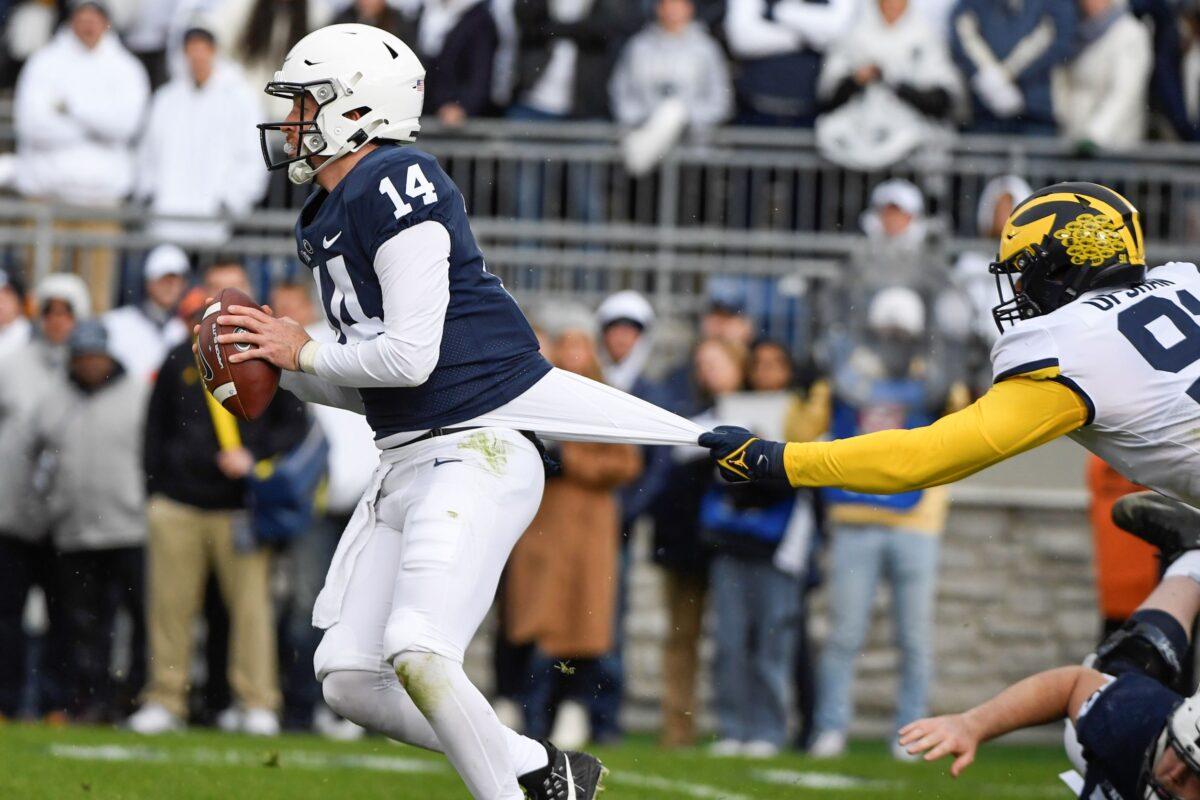 Penn State quarterback Sean Clifford (14) looks to escape a tackle attempt by Michigan defensive end Taylor Upshaw (91) in the first quarter of an NCAA college football game in State College, Pa., on Nov. 13, 2021. (Barry Reeger/AP Photo)