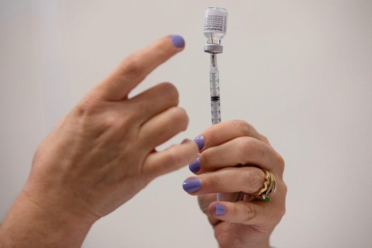 A nurse fills up syringes for patients as they receive their COVID-19 booster vaccination during a Pfizer-BioNTech vaccination clinic in Southfield, Mich., on Sept. 29, 2021. (Emily Elconin/Reuters)