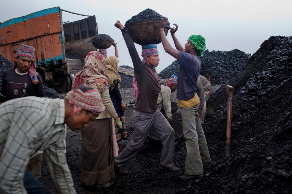 Workers load coal onto a truck at a coal depot near Lad Rymbai, in the district of Jaintia Hills, India, on April 14, 2011. The victims of the coming coal crisis may remain invisible in much of the media: the unemployed American miner, the French retiree, the rural Indian farmer, and many more. (Daniel Berehulak/Getty Images)
