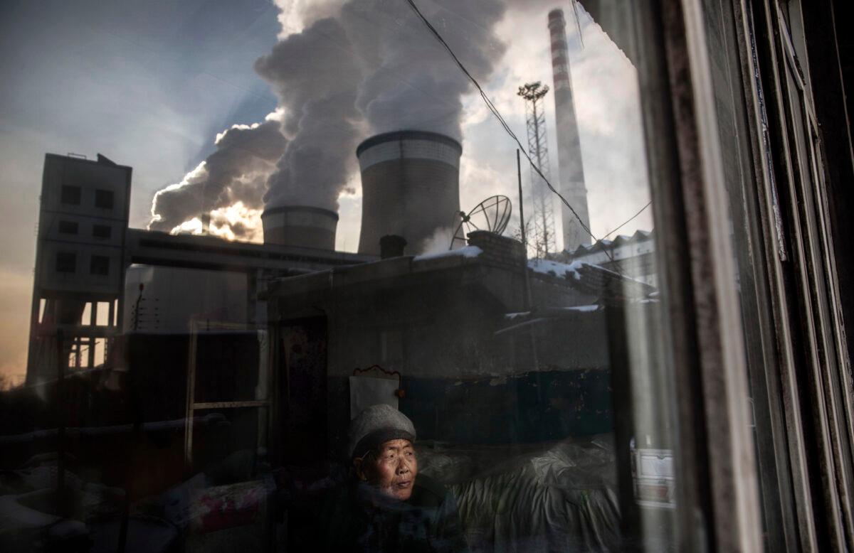A Chinese resident looks out the window of her house next to a coal-fired power plant in Shanxi Province, China, on Nov. 26, 2015. As winter approaches amidst worldwide energy woes, coal shortages are becoming a global crisis. (Kevin Frayer/Getty Images)