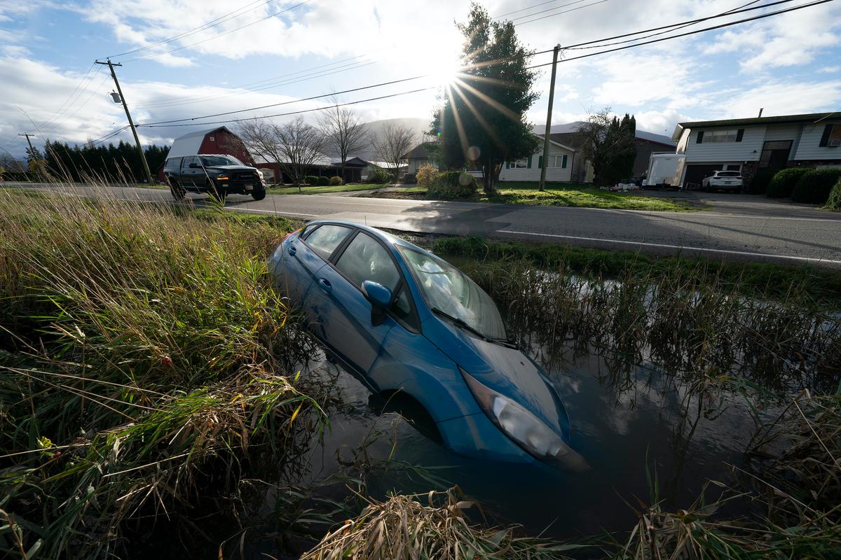A car is seen in a flooded ditch along a road in Chilliwack, B.C., on Nov. 16, 2021. (Jonathan Hayward/The Canadian Press)